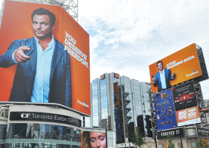outdoor signage that shows a large billboard for Freedom Mobile with spokesperson Will Arnet